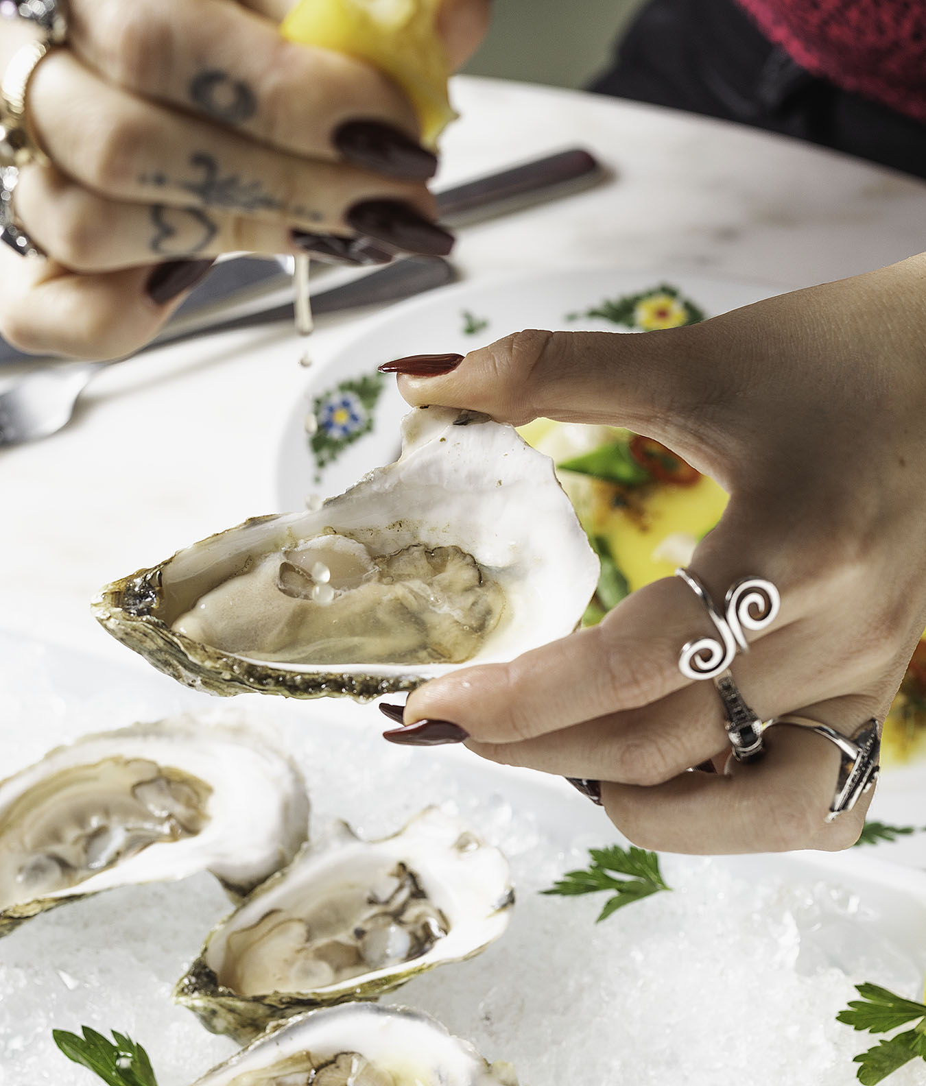 hands sqeezing lemon onto an oyster
