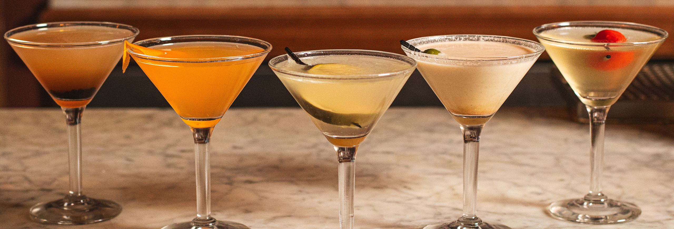 a row of 5 colored different martinis, inspired by salad flavors