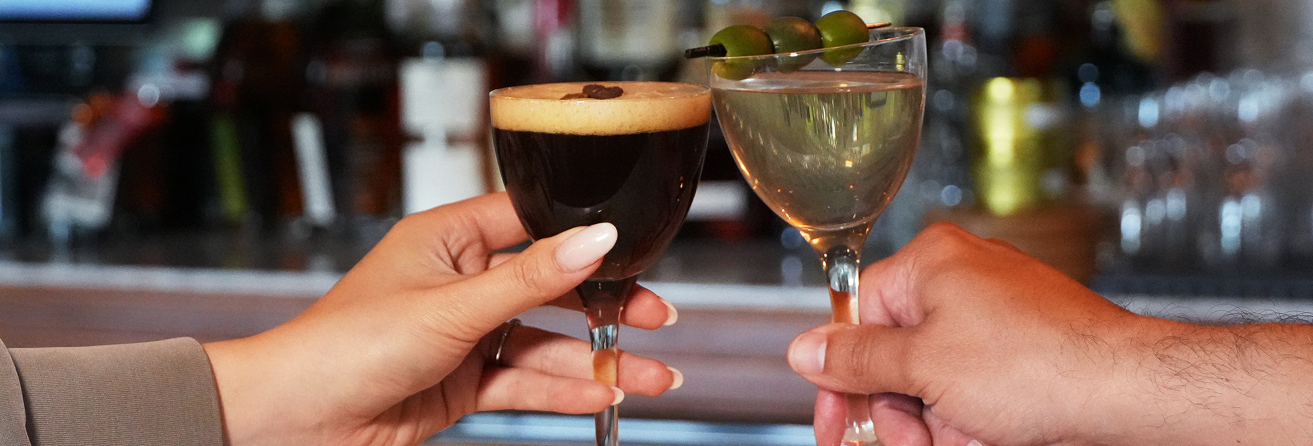 an espresso martini cheers-ing with a dirty martini