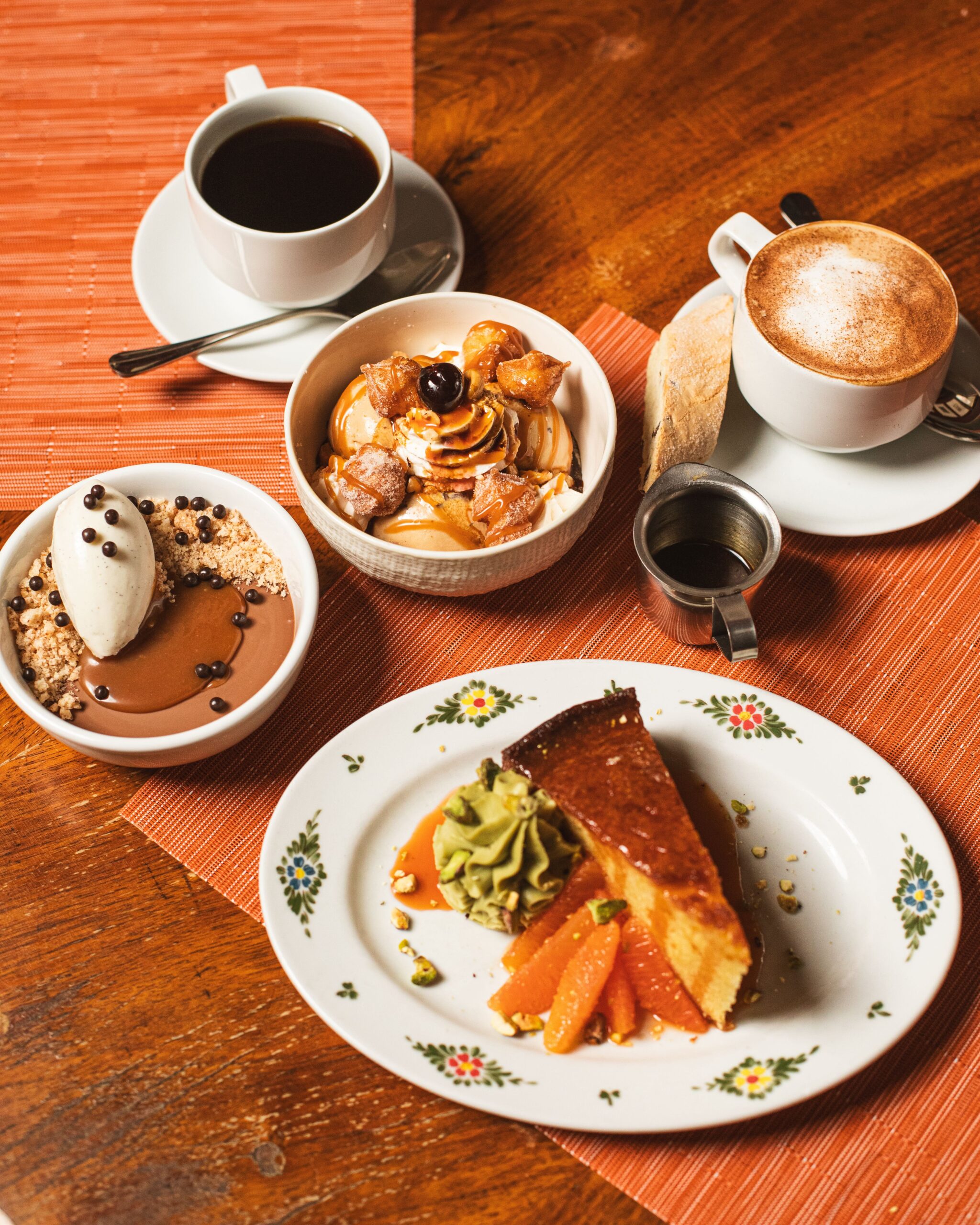 desserts on a wooden table, include a coffee, budino (milk chocolate crema), torta (olive oil cake), and gelato affogato.