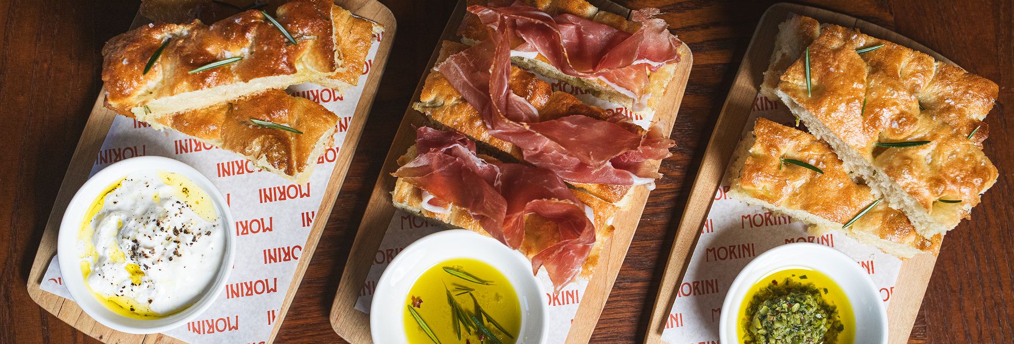 three wood boards with three styles of foccacia and dips