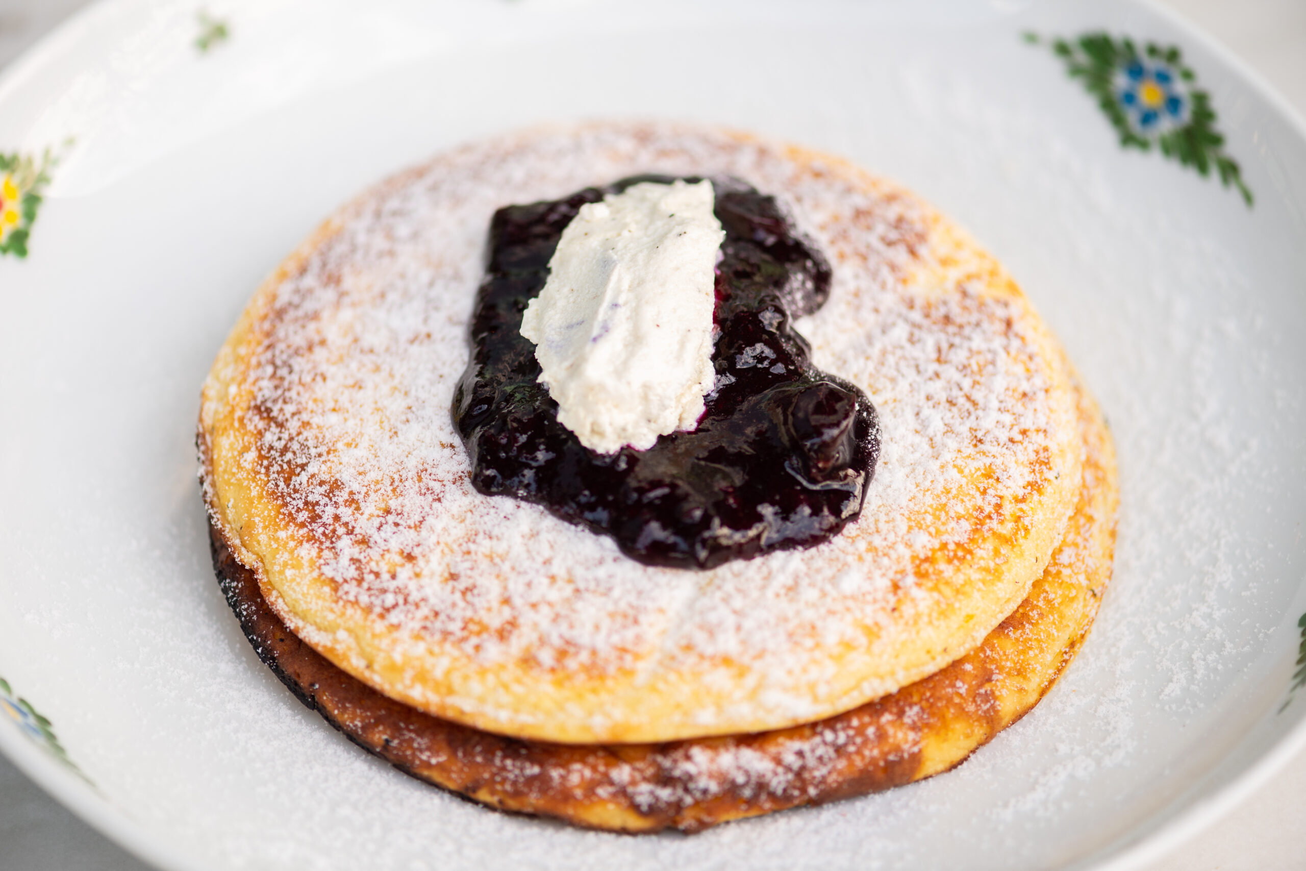 pancakes with powdered sugar, fruit compote, and whipped cream