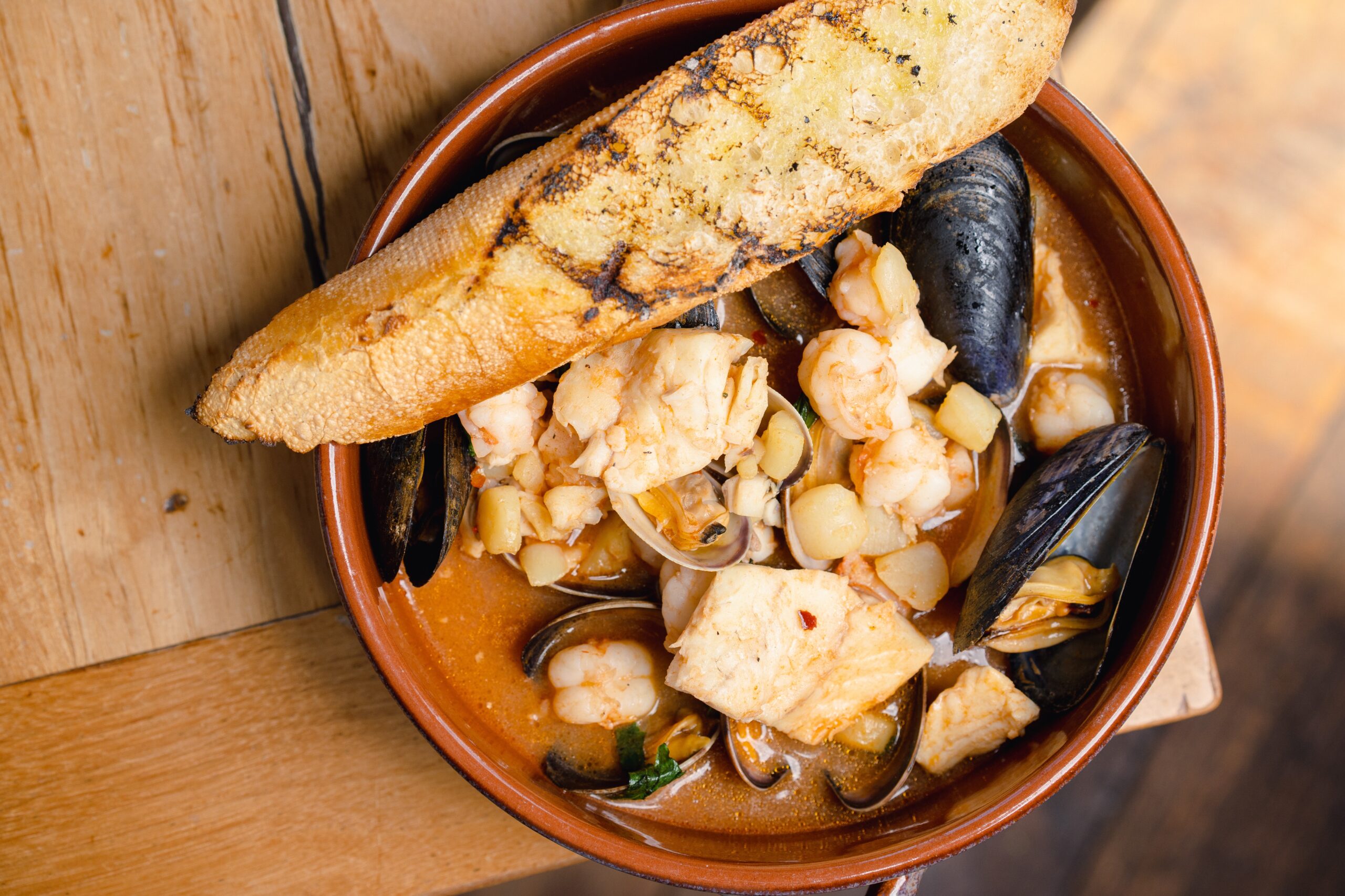 a bowl of a mixed seafood stew with a crostini