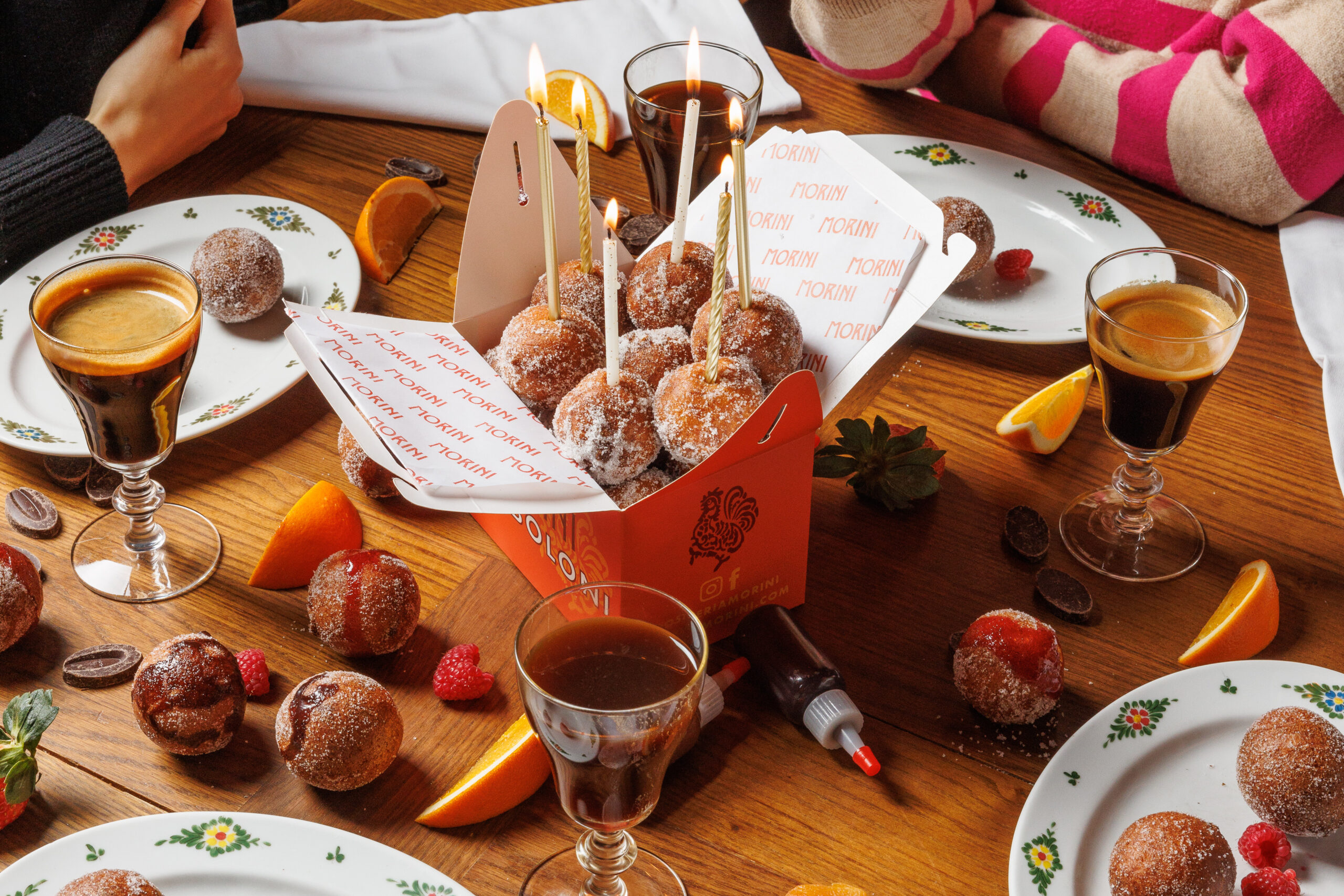 box of bomboloni desserts on a table crowded with the remnants of a good meal