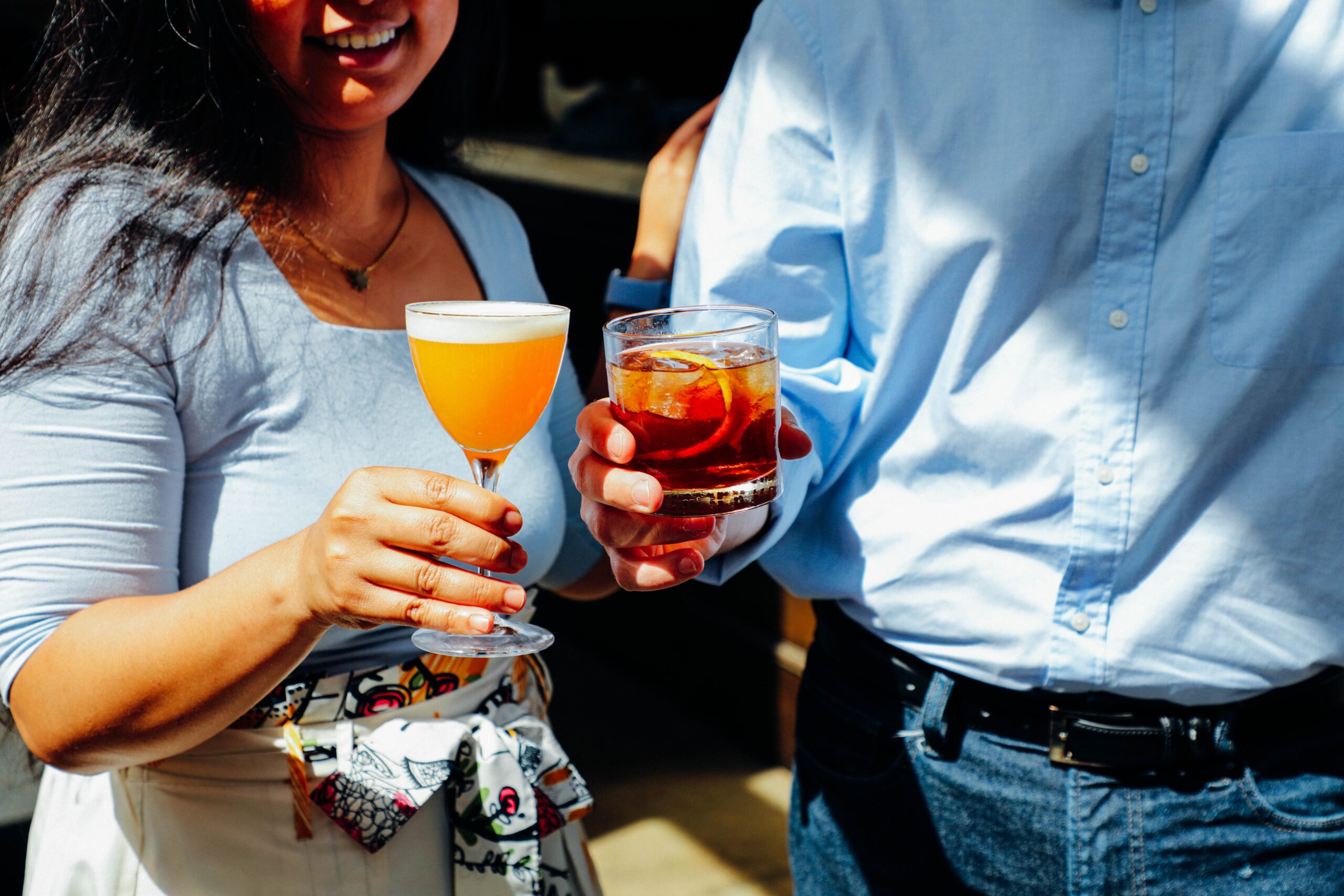 a man and a woman each holding a cocktail