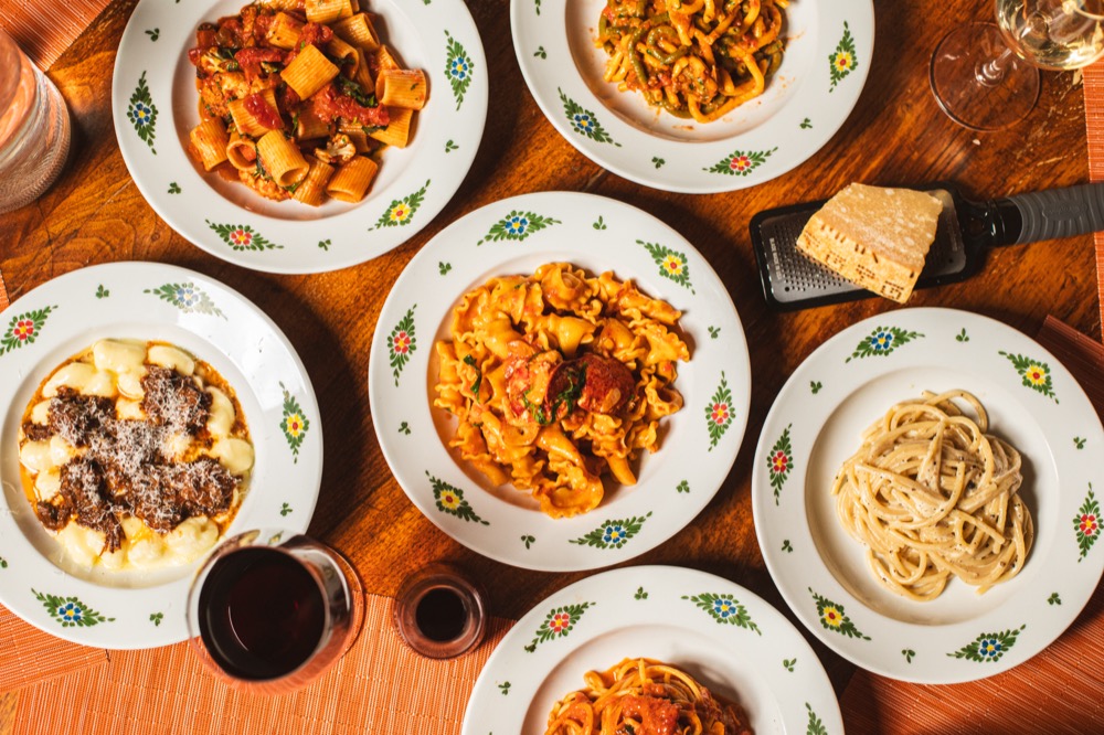 a group of decorated dishes filled with various pastas including rigatoni, bucatini, and spaghetti